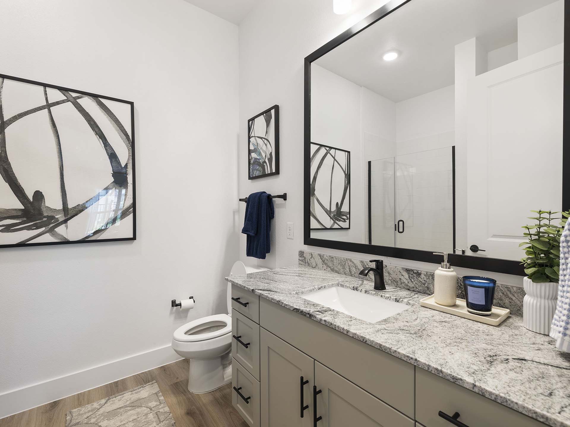 Evergrove apartment bathroom with large mirror and lights.